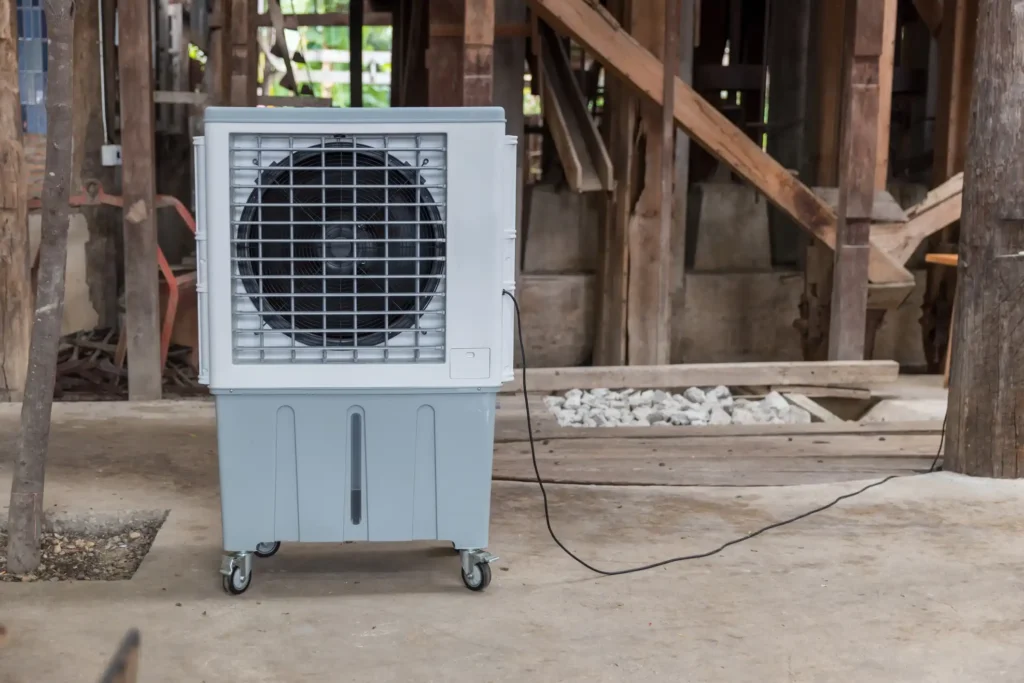 Portable gray and white evaporative cooler or swamp cooler on wheels in a construction area.