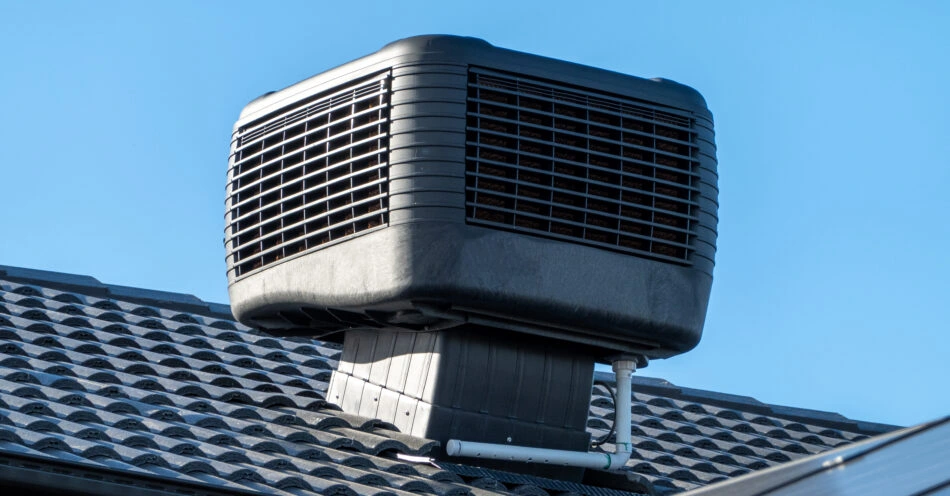 Evaporative cooler mounted on a dark roof.
